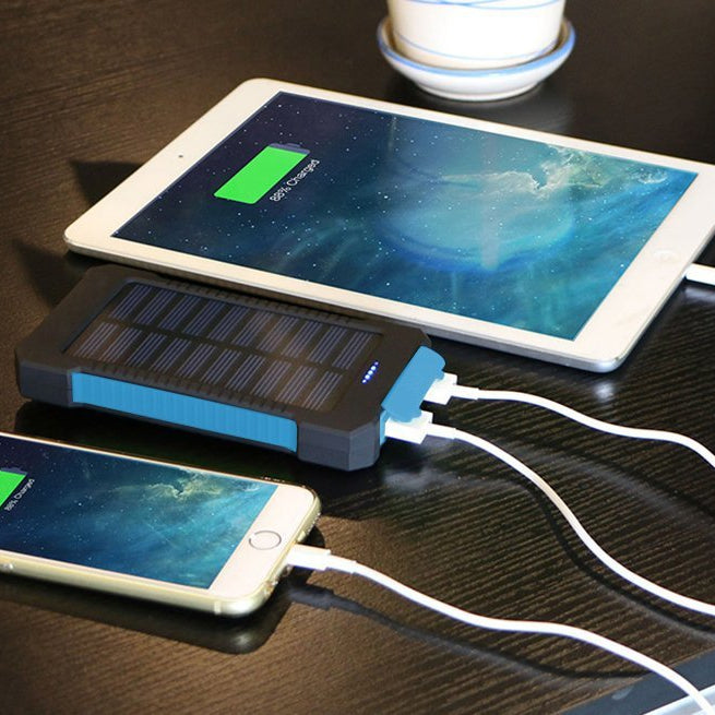 Solar power bank charging a smartphone and tablet on a dark surface